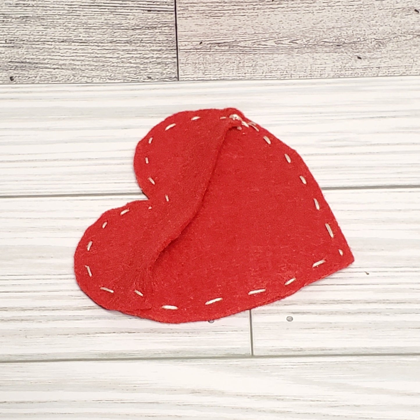 Felt heart with white stitching to make a pocket and hold small things. 